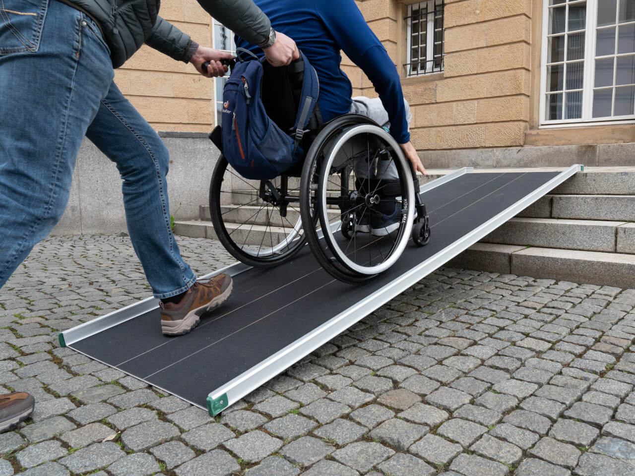 rollstuhlfahrer mit hilfsperson nutzt rtsd rollstuhlrampe fuer 4 stufen