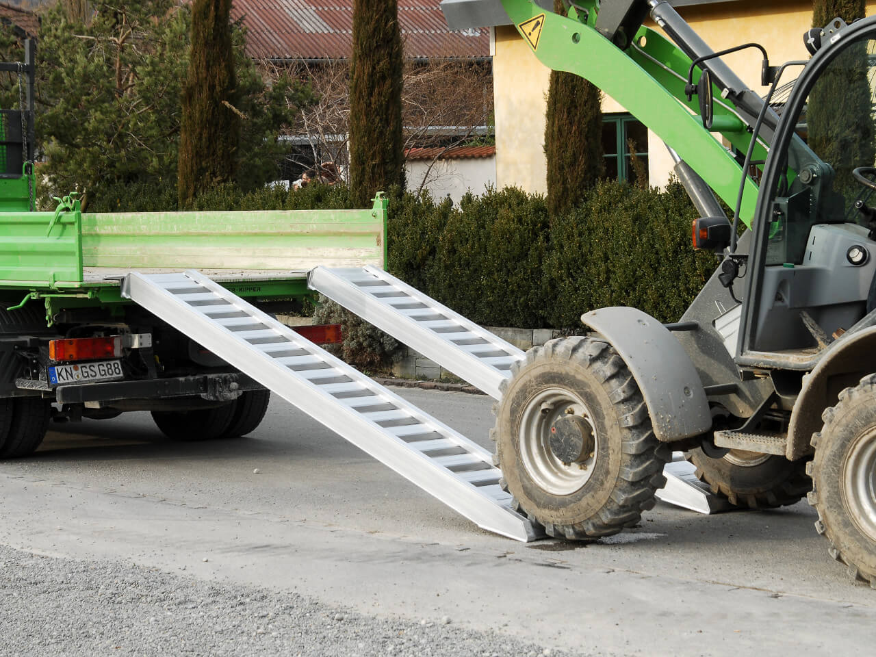 bagger faehrt ueber avss auffahrrampen auf transportfahrzeug auf