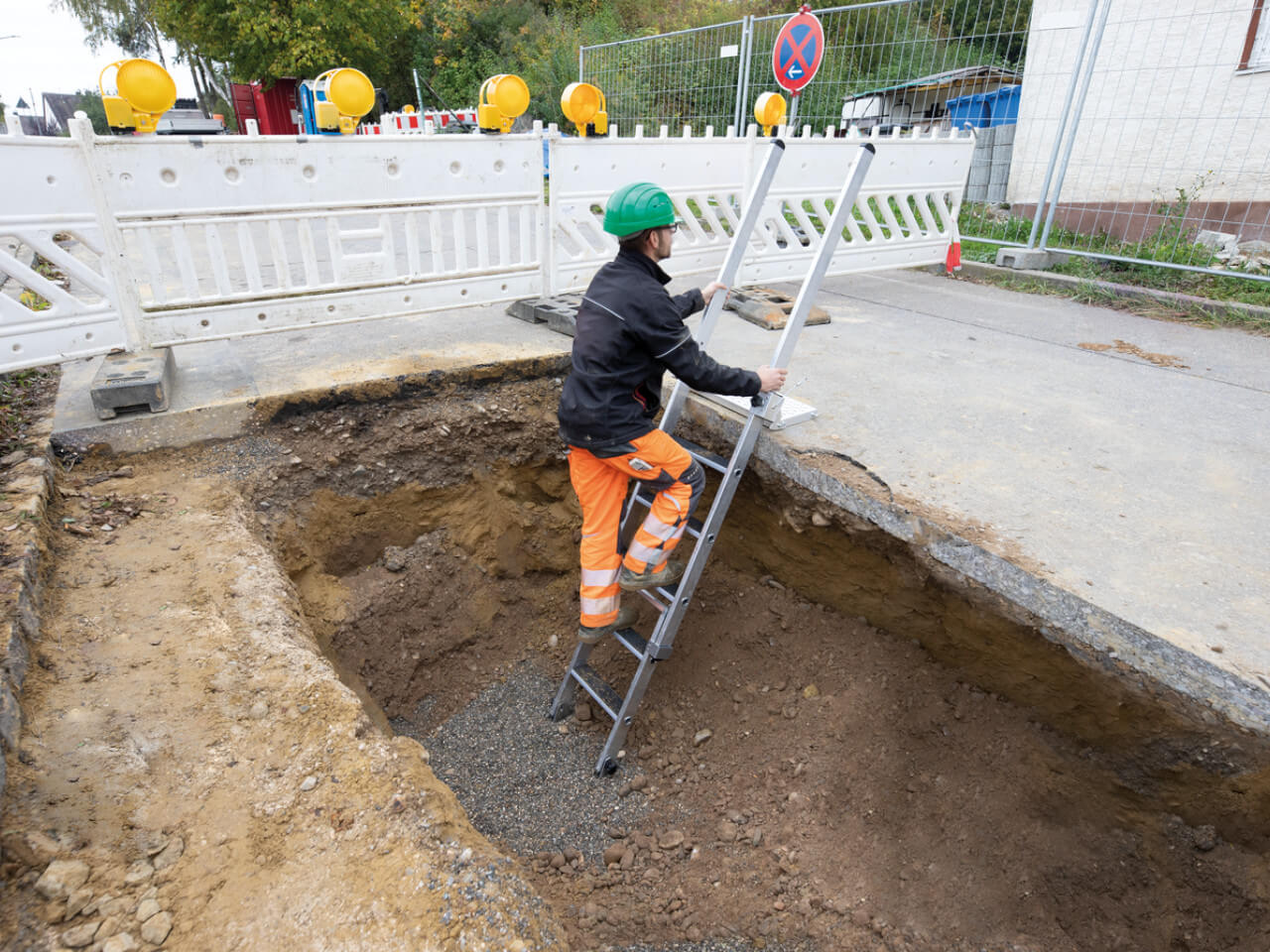 bauarbeiter steht auf einer munk baugruben stufen leiter auf einer baustelle