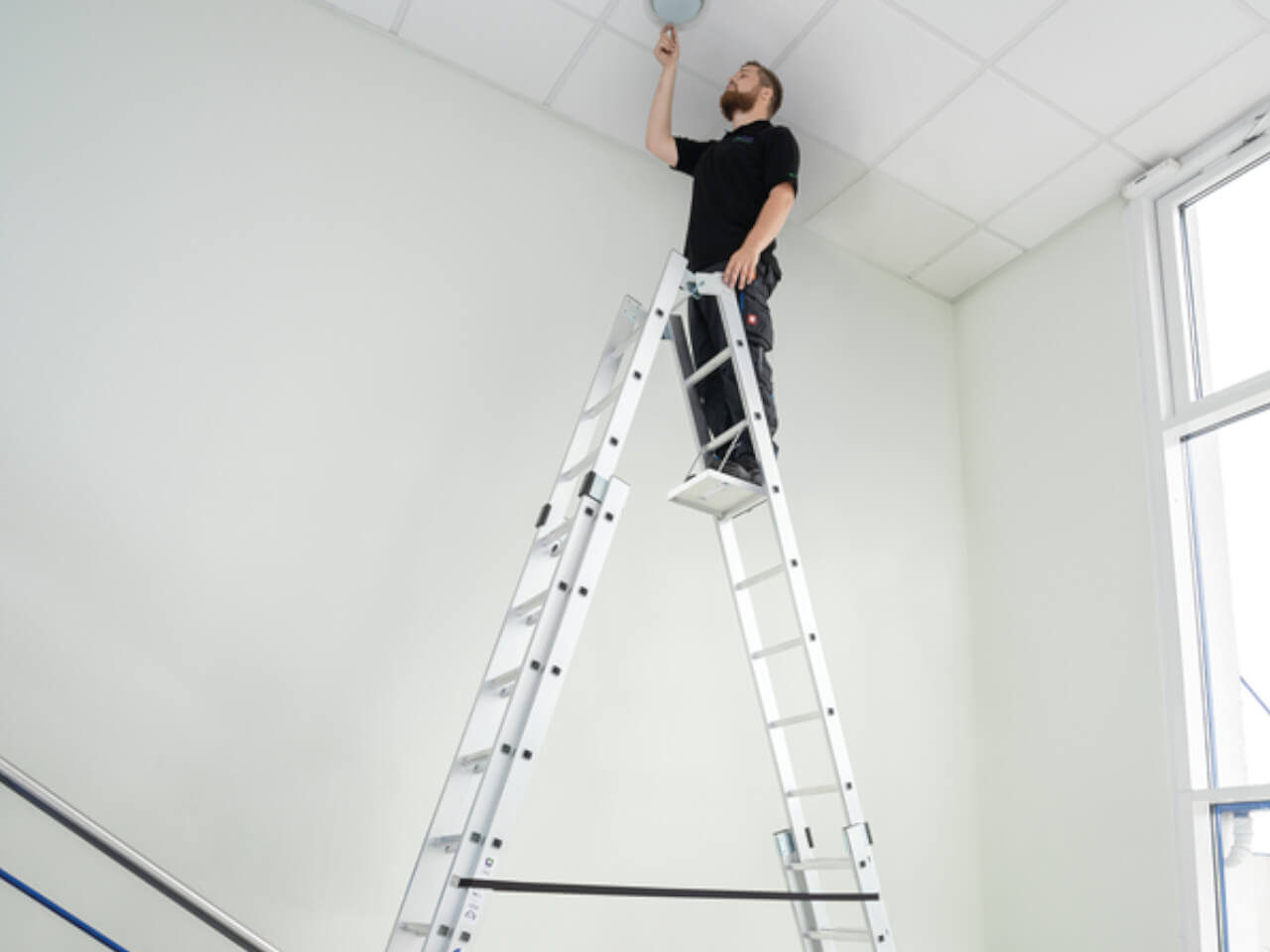 handwerker auf einer munk sprossen stehleiter 4-teilig mit nivello traverse