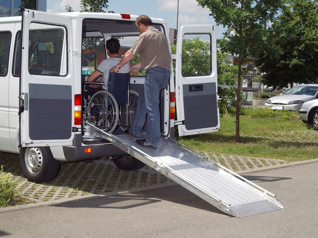 rollstuhlfahrer mit hilfsperson nutzen die eingebaute rollstuhlrampe rlk