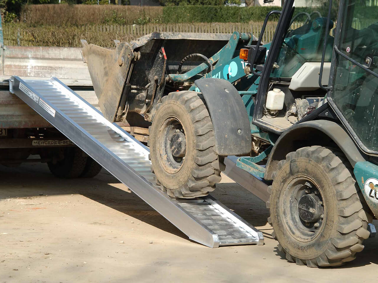 schwere baumaschine faehrt ueber auffahrrampen auf ein anhaenger