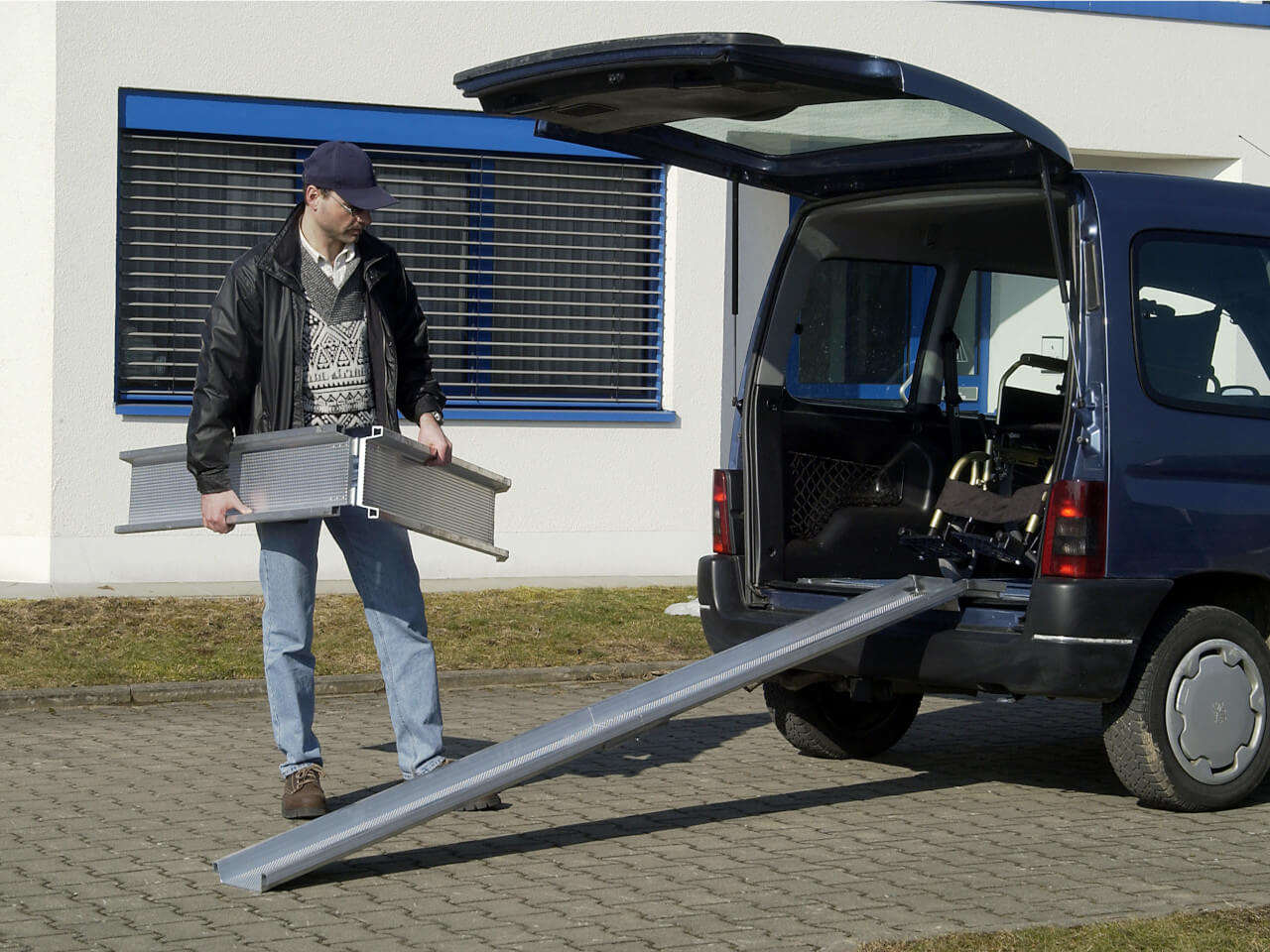 mann haelt klappbare rollstuhlschiene in der hand