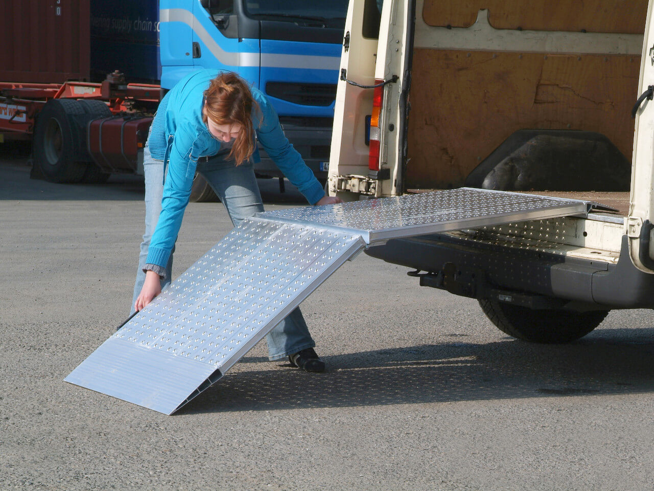 frau legt eine klappbare breite auffahrrampe am transporter an