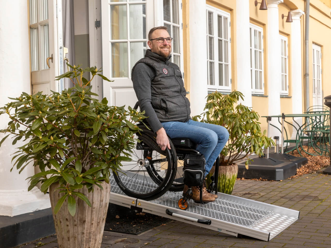 mann im rollstuhl nutzt rollstuhlrampe als barrierefreie loesung - rollstuhlrampe erhaeltlich im thiele-shop