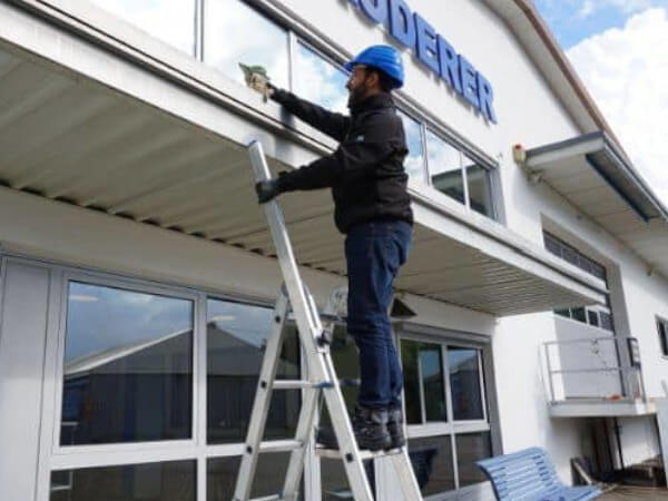 handwerker haelt sich an leiter-handlauf fest