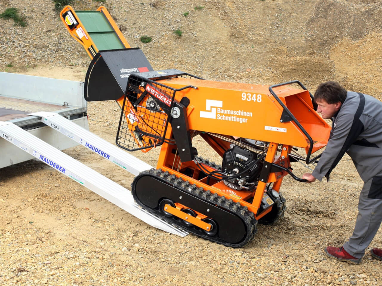 baumaschine mit gummiketten wird mithilfe von auffahrrampen verladen