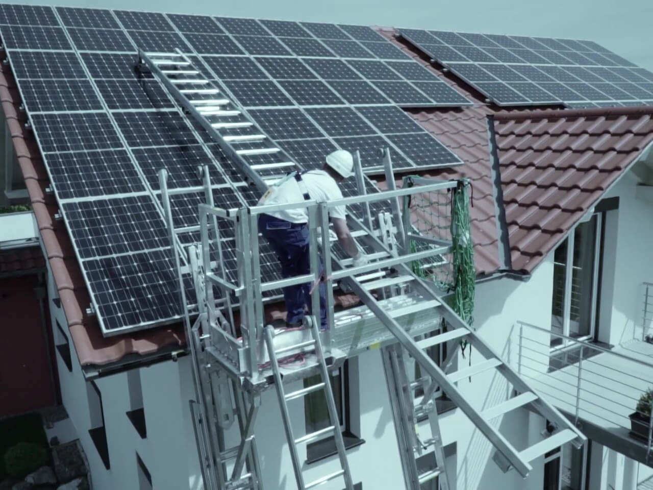 solateur nutzt leiter zur wartung einer photovoltaik-anlage auf dem dach