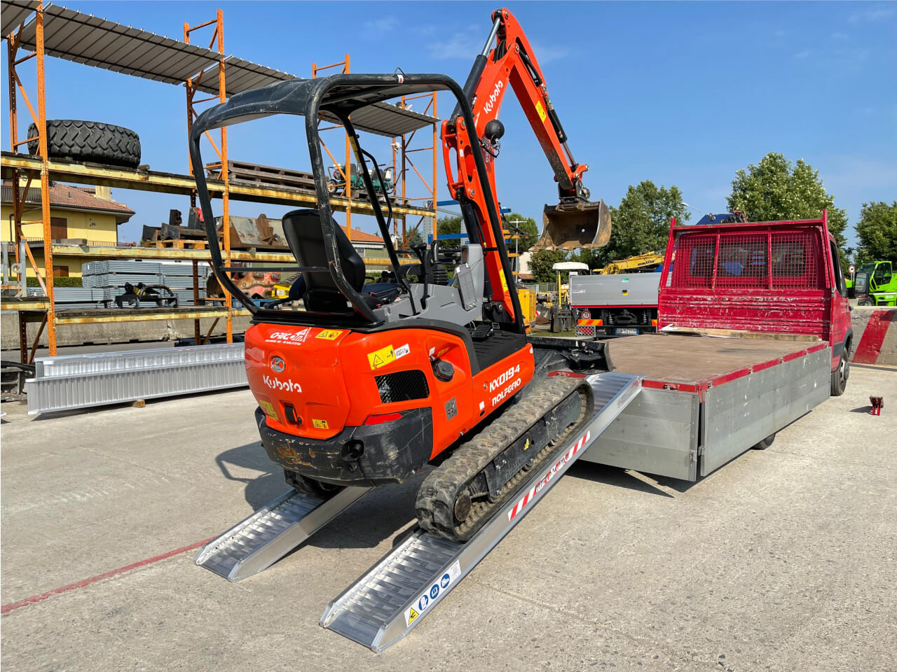 roter bagger faehrt ueber m115 auffahrrampen auf transportfahrzeug hoch