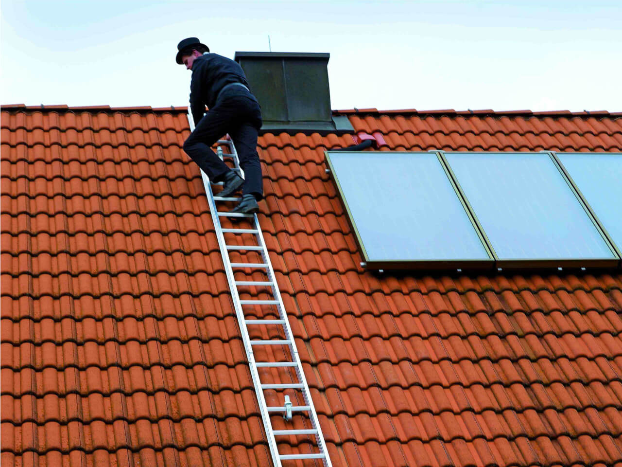 dachdecker oder schornsteinfeger nutzt eine dachleiter fuer arbeiten am kamin