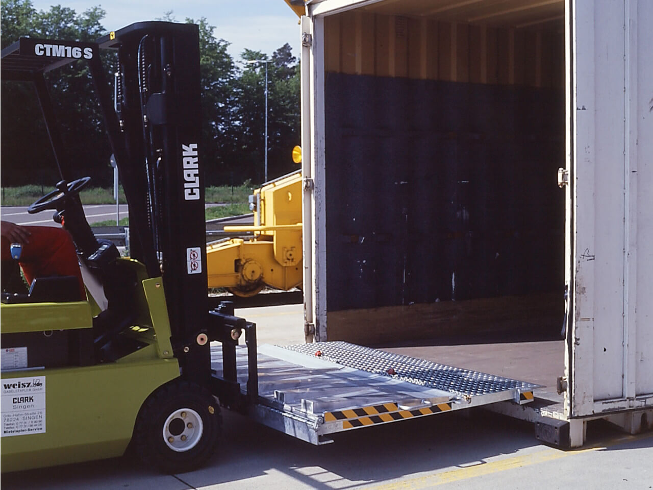 stapler transportiert ueberladebruecke zu einen container