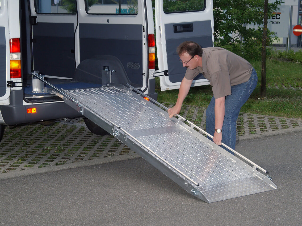 mann greift nach einbaurampe am transporter