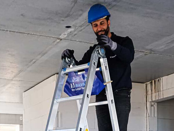 handwerker legt sachen in die werkzeugtasche einer alu leiter von bavaria