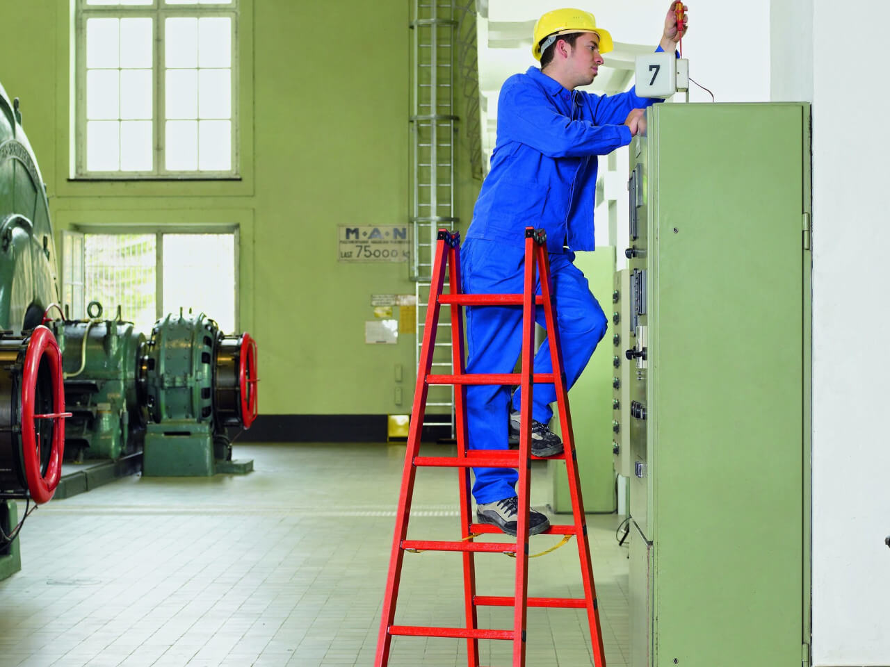 elektriker auf einer gfk stehleiter fuer arbeiten an unter spannung stehenden teilen