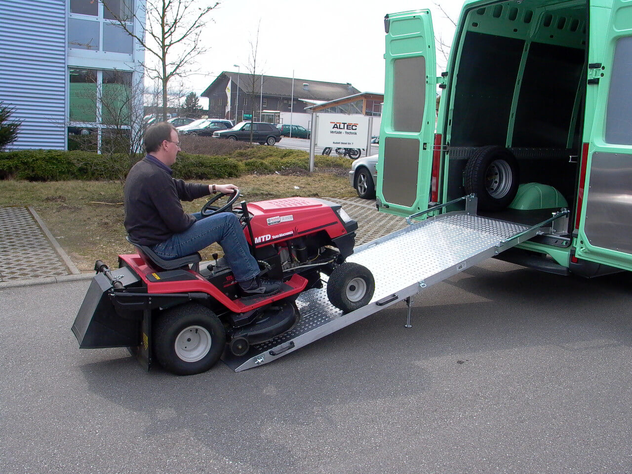 rasentraktor faehrt ueber auffahrrampe in transporter