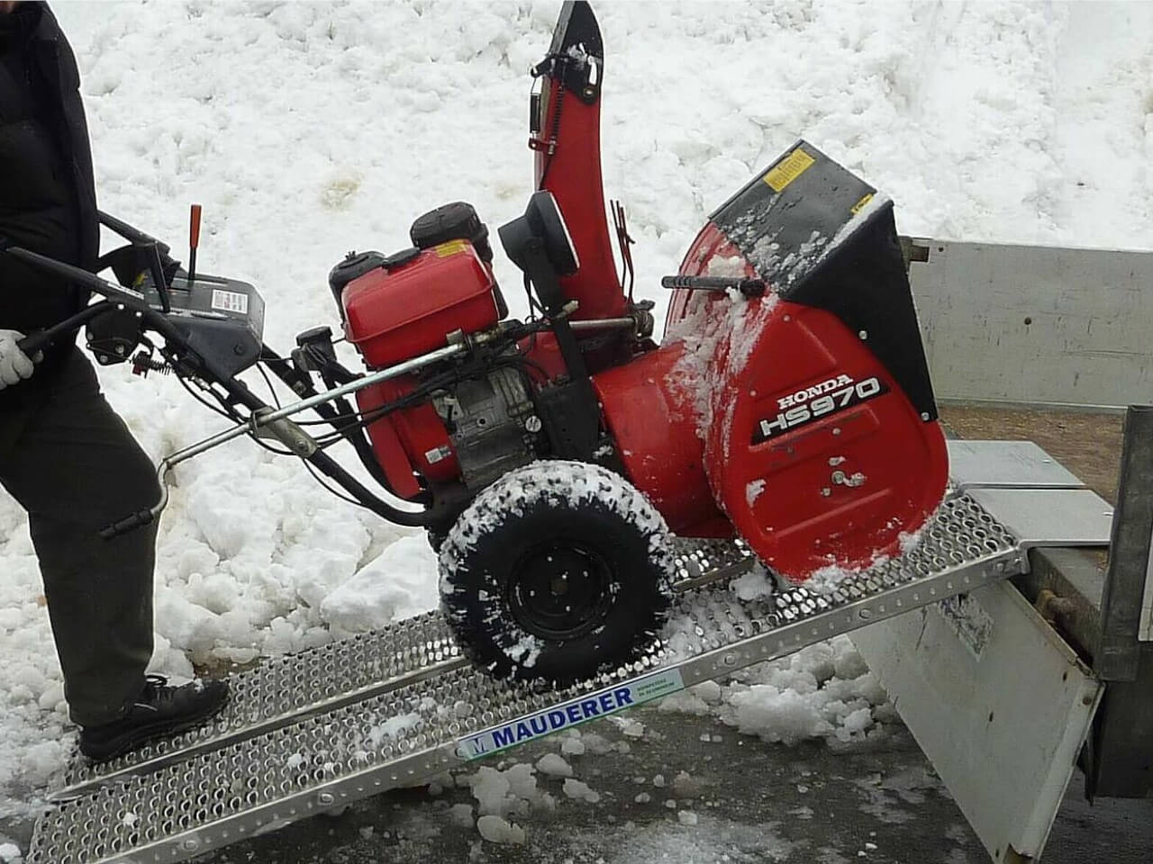 schneefraese wird mithilfe von auffahrrampen verladen