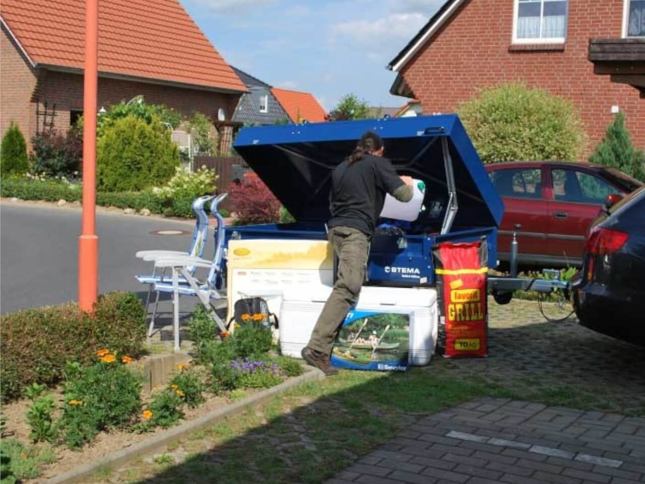 mann lagert camping zubehoer im schliessbaren anhaenger blue man