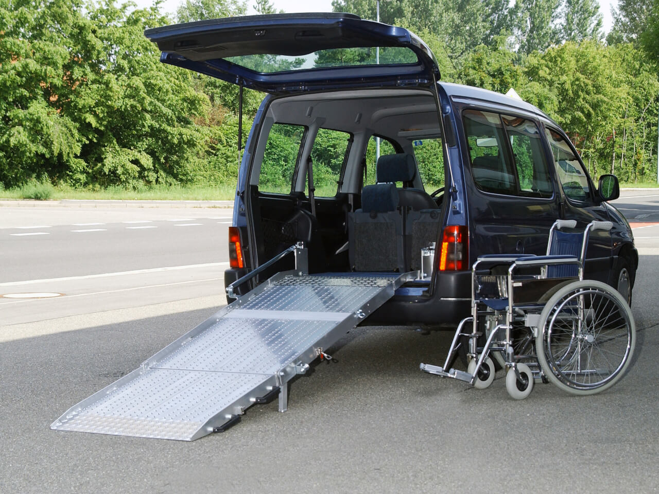 rollstuhl steht neben kleinfahrzeug caddy mit fest verbauter rollstuhlrampe